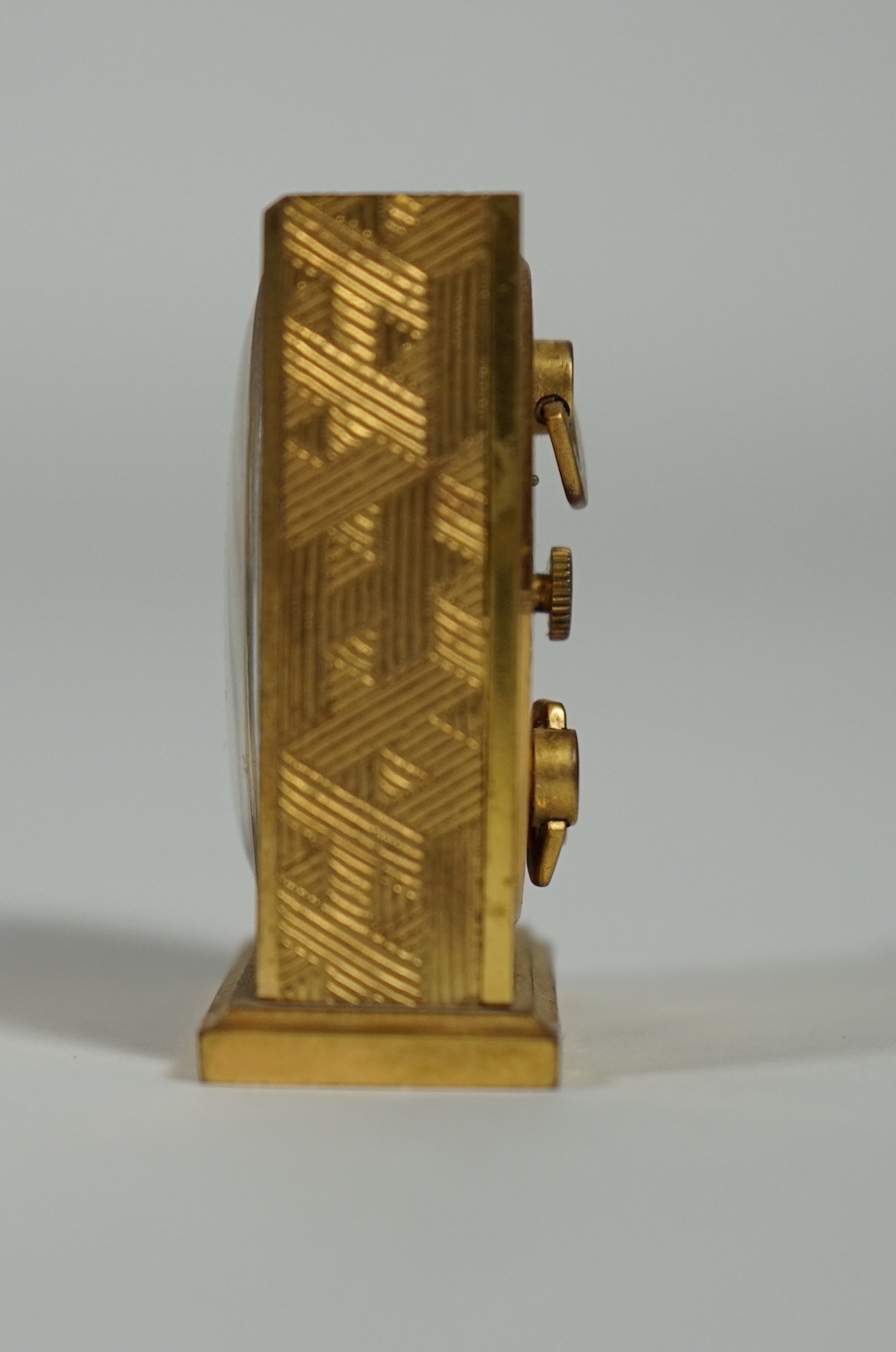 A Hermès travel alarm clock in gilded brass chiselled with H enchassés, height 5cm